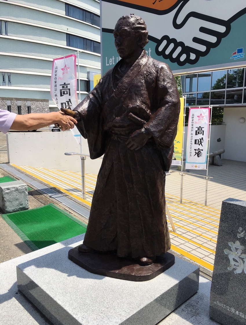 等身大ブロンズ像の龍馬と握手し...