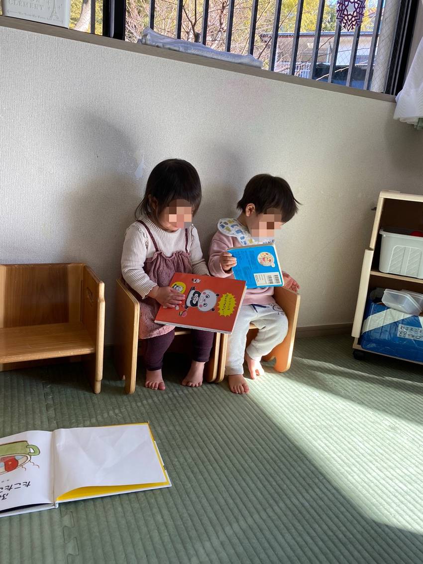 陽だまりの中で並んで絵本を読ん...